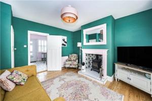 a living room with green walls and a television and a fireplace at St Mary's Cottage in Boston Spa