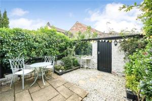 a patio with a table and chairs in a garden at St Mary's Cottage in Boston Spa