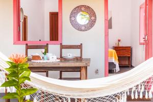 a hammock in a living room with a table at Pousada Vila Rosa - Caraiva in Caraíva