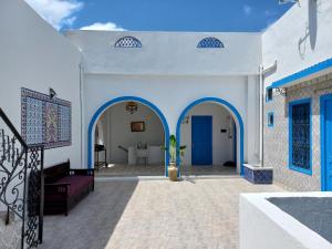 a white house with blue doors and a potted plant at DAR Jamila à 8021 Béni khalled Tunisie in Dawwār al Frinine
