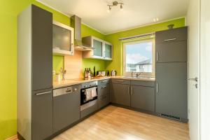 a kitchen with gray cabinets and green walls at Dolomites Bungalow Eifelsteig w view Terrace BBQ in Gerolstein