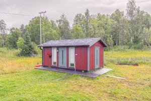 un pequeño cobertizo rojo sentado en un campo en Trivelig hytte i Senja., 