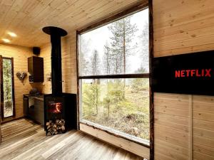 a living room with a fireplace and a large window at Unique Cabin with Breathtaking Northern Light View in Rovaniemi