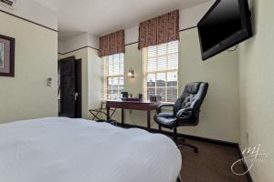 ein Schlafzimmer mit einem Bett, einem Stuhl und einem Schreibtisch in der Unterkunft Hotel Seville in Harrison