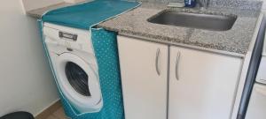 uma máquina de lavar roupa numa cozinha ao lado de um lavatório em Acogedor departamento 1 dormitorio em El Palomar