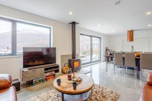 a living room with a fireplace and a tv at Svarga Mountain View in Kinlochleven