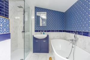 a blue tiled bathroom with a tub and a sink at Svarga Mountain View in Kinlochleven