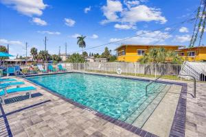 a swimming pool with blue chairs and a fence at Madeira Del Mar 205 in St Pete Beach