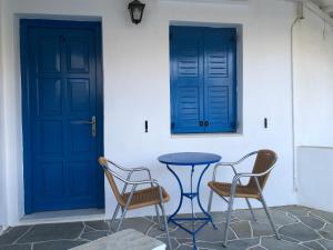 two chairs and a table in front of two blue doors at Petradi Residence Sifnos in Platis Gialos