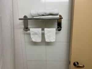 un baño con toallas blancas en un toallero. en Atlantic Motor Inn, en Brooklyn