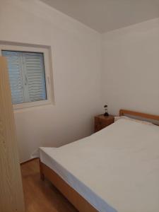 białe łóżko w pokoju z oknem w obiekcie Apartmani Vesna w mieście Miškovići