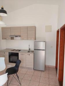 uma cozinha com um frigorífico de aço inoxidável e uma cadeira preta em Apartmani Vesna em Miškovići