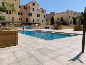a swimming pool in the middle of a courtyard with buildings at Résidence les dromadaires in Gruissan +20 photos