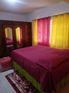 1 dormitorio con 1 cama con cortinas amarillas y rojas en A Piece of Paradise, en Santa Cruz