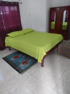 Una cama con una manta verde en una habitación en A Piece of Paradise, en Santa Cruz