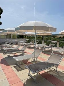 eine Reihe von Stühlen und einem Sonnenschirm auf einer Terrasse in der Unterkunft Residence San Luca Vieste in Vieste