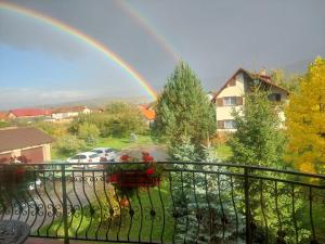 a rainbow in front of a balcony with a yard at Vila Old Cars in Cristian