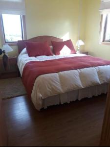 1 dormitorio con 1 cama grande con almohadas rojas en Cabañas Frange en Puerto Natales