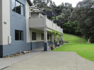 a building with a stairway next to a green yard at Cornwallis Palms in Auckland