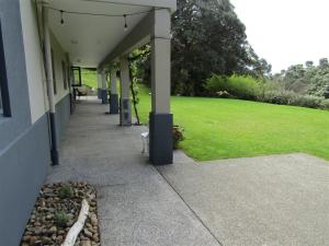 a building with a walkway next to a green field at Cornwallis Palms in Auckland