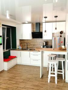 una cucina con mobili bianchi, un tavolo e sgabelli di Studio Apartment Center a Kremenčuk