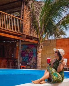 une femme assise à côté d'une piscine avec un verre dans l'établissement Blue Ocean, à Máncora