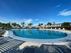 a large swimming pool with chairs and palm trees at Beachfront Family Escape 3BR Samaria Club de Playa in Gaira