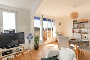 uma sala de estar com uma televisão e uma mesa e cadeiras em Cabana & Grand appartement cosy - Parking & Balcon em Villefranche-sur-Saône