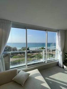 a living room with a large window with a view of the ocean at Vacation Apartment By The Beach in Bat Yam