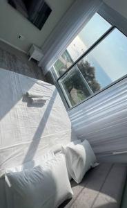 a bedroom with a large window and white pillows at Vacation Apartment By The Beach in Bat Yam