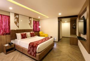 a hotel room with a bed and a flat screen tv at Mango Hill Central Chennai in Chennai