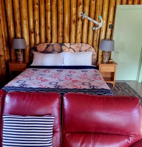 a bed in a room with a red leather couch at High Falls Motel & Cabins in Wawa