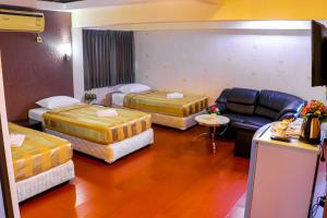 a hotel room with three beds and a couch at Visiting Card Hotel & Resort in Bangkok