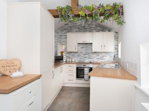 a kitchen with white cabinets and a brick wall at Highgate in Kirklinton