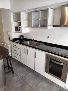 a kitchen with white cabinets and a sink and a stove at Depto 2 amb- Punta Mogotes- ideal para altos in Mar del Plata
