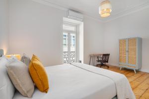 a white bedroom with a large white bed with yellow pillows at Brand New Luxury 4-Bed with Riverside Views & AC in Lisbon