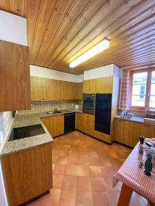 a large kitchen with wooden cabinets and a table at Casa Lalla affittasi nel centro di Poschiavo in Poschiavo