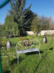 un banco de metal sentado en el césped en un campo en Chaumière avec sa toiture recouverte de chaume !!!, en Donnemain-Saint-Mamès