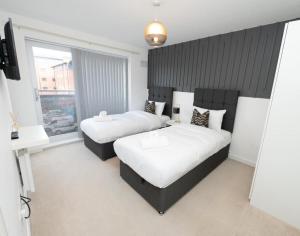 a bedroom with two beds and a large window at Grand Station Suite in Wolverhampton