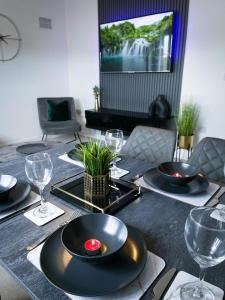 einen Esstisch mit schwarzen Tellern und Weingläsern in der Unterkunft Grand Station Suite in Wolverhampton