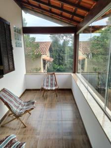 a room with a balcony with chairs and windows at Hostel Ares do Mundo in Miguel Pereira