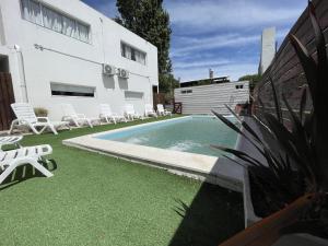 una piscina junto a una casa con sillas y una casa en Apart Nivel Cero, en Monte Hermoso