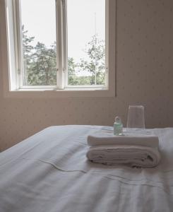 a white bed with towels on it with a window at Turistgården Töcksfors in Töcksfors