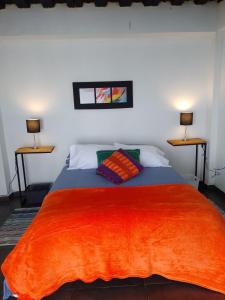 um quarto com um grande cobertor laranja numa cama em Casablanca Choachi em Choachí