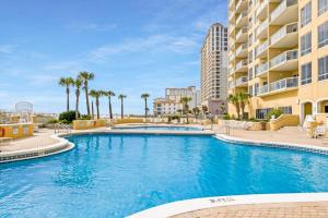 una piscina en un complejo con palmeras y edificios en The Beach Bounce en Pensacola Beach