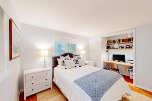 a white bedroom with a bed and a desk at Pine Cottage in Seal Harbor