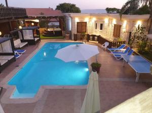 a swimming pool with chairs and an umbrella at The Pearl of the Golan - Pnina BaGolan in Had Nes