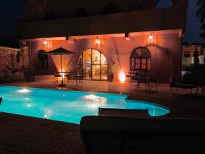 a swimming pool in front of a house at night at Villa nouran in Ghazoua
