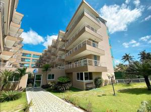 a tall building with palm trees in front of it at Ap lindo, moderno, confortável, novo! in Cumbuco