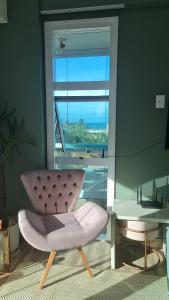 una silla rosa sentada frente a una ventana en Ap lindo, moderno, confortável, novo!, en Cumbuco